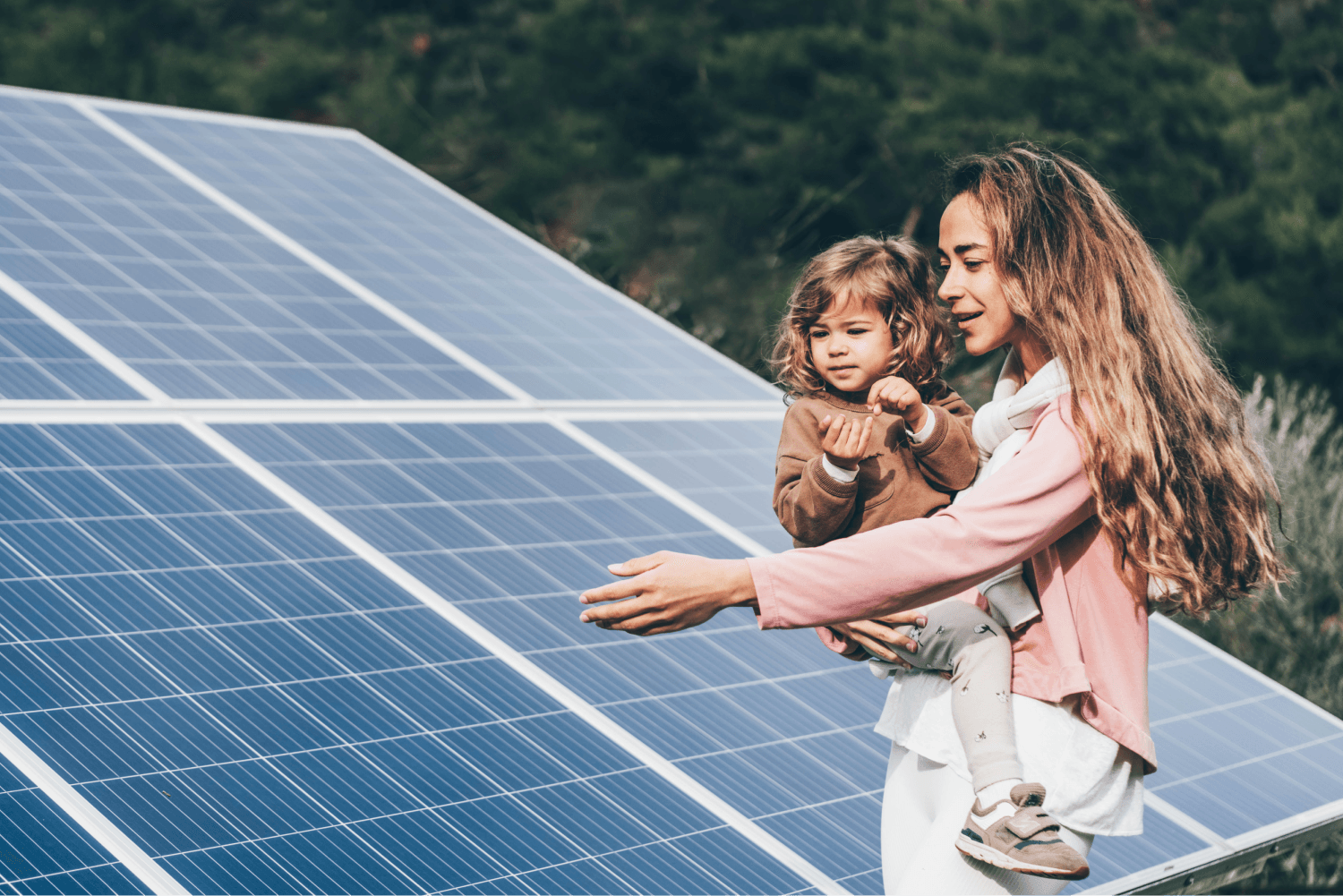 Mutter mit Kind auf dem Arm zeigt auf Solaranlage